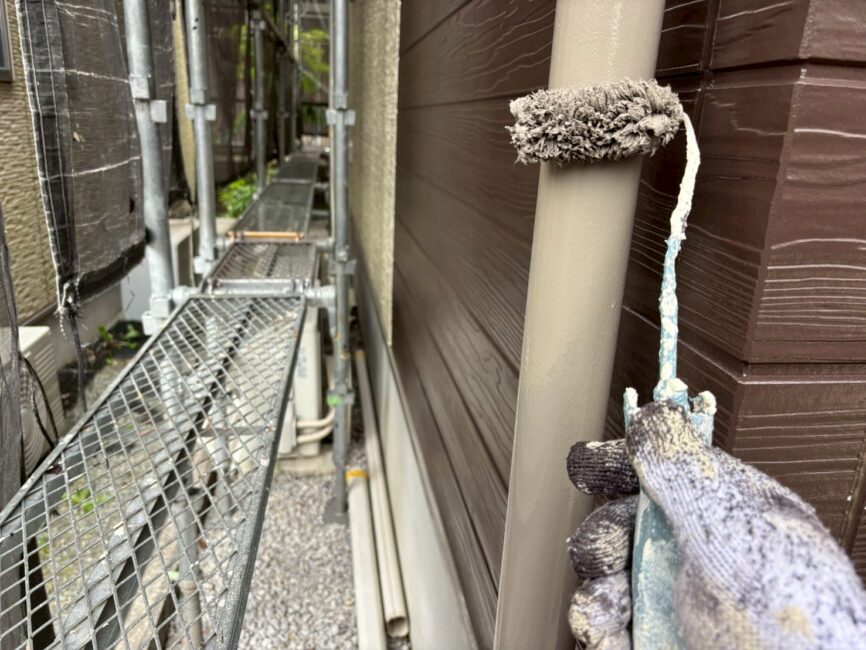 写真：雨樋をローラーで塗装している様子